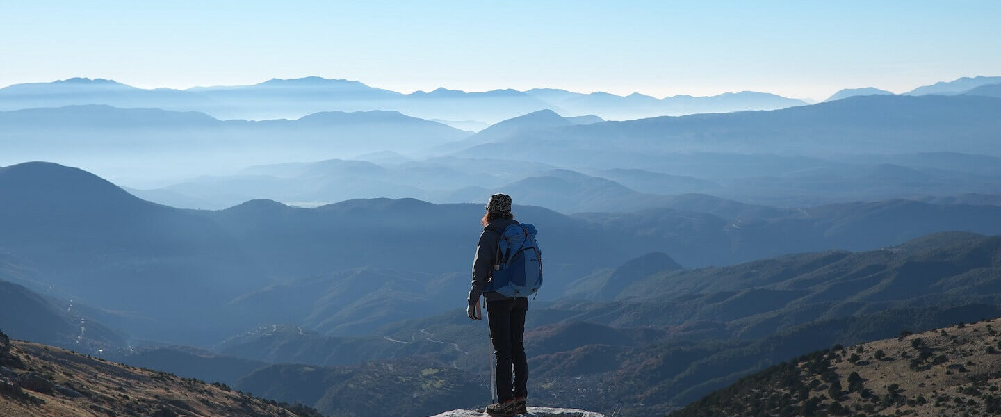 ESG Wesentlichekitsanalyse Symbol Frau überblickt Berglandschaft von Gipfel